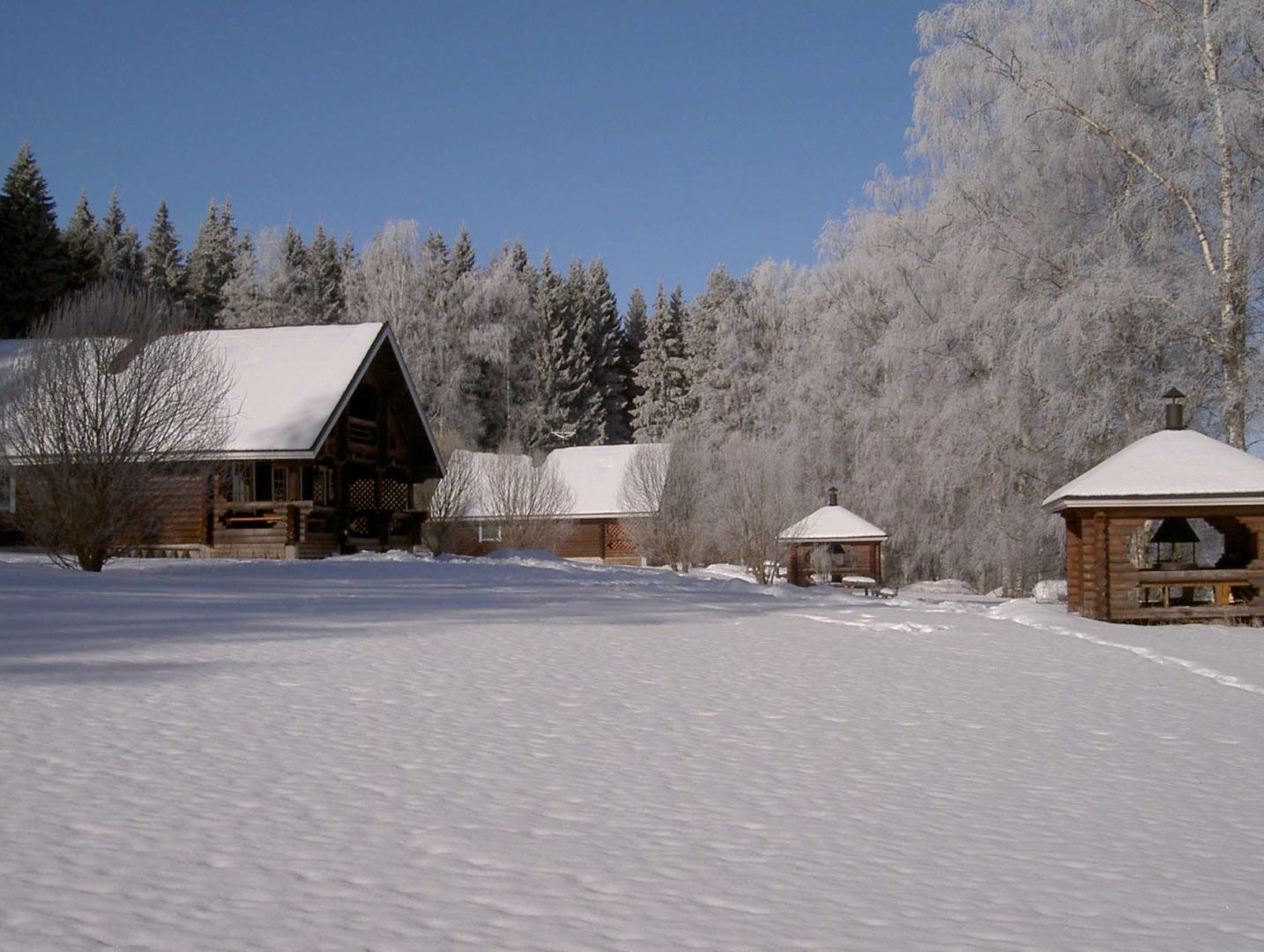 Karhunluolan ja Oravanpesän talvinen piha-alue, mökit sijaitsevat n.40m päässä toisistaan.