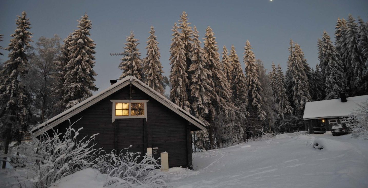 Kuutamo loistaa mökkien yllä talviyössä.