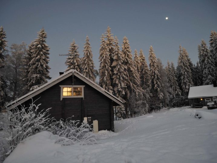 Kuutamo loistaa mökkien yllä talviyössä.