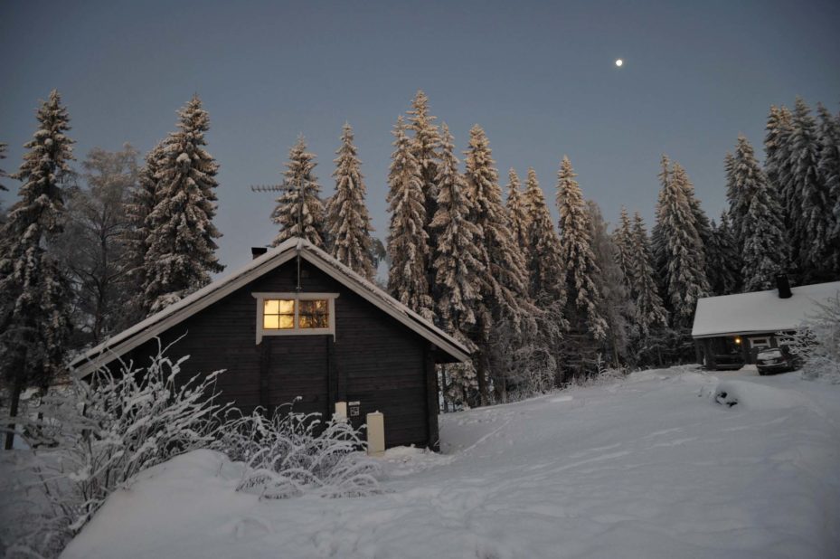 Kuutamo loistaa mökkien yllä talviyössä.