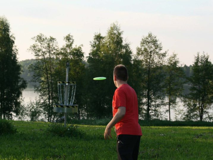Frisbeegolfia kesäillassa Kanta-Hämeessä, kiekko matkalla kohti koria.
