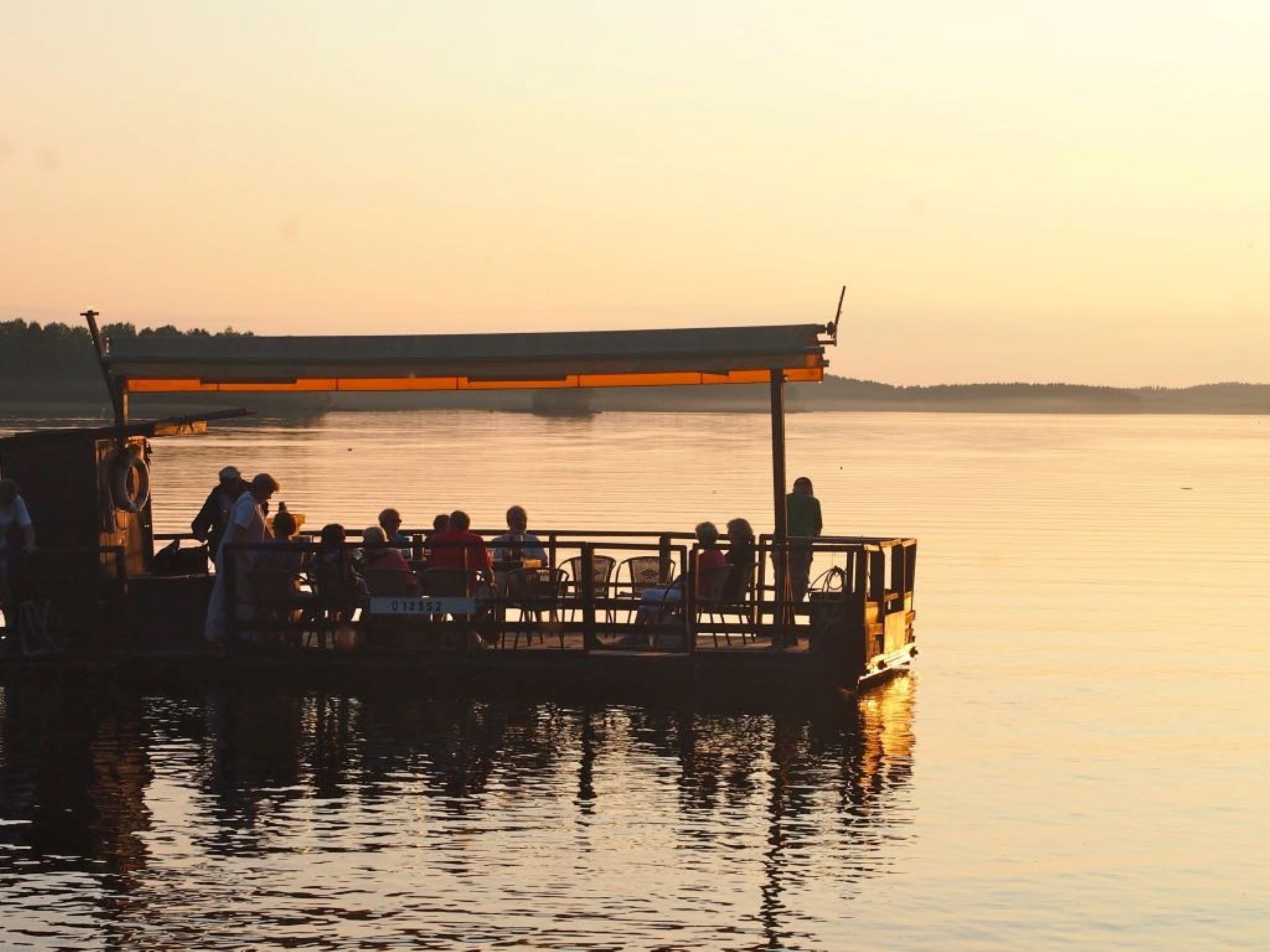 Leppäniemessä suunniteltu ja toteutettu lautta lipuu asiakkaat kyydissä lautturin ohjaamana kesäillassa Iso-Roineella.