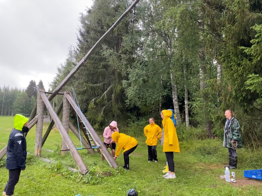 Kisakenttä. Aktiviteetit lomalla Hauholla: Trebuchet-katapultin viritystä sateisessa säässä iloisen polttariporukan kanssa.