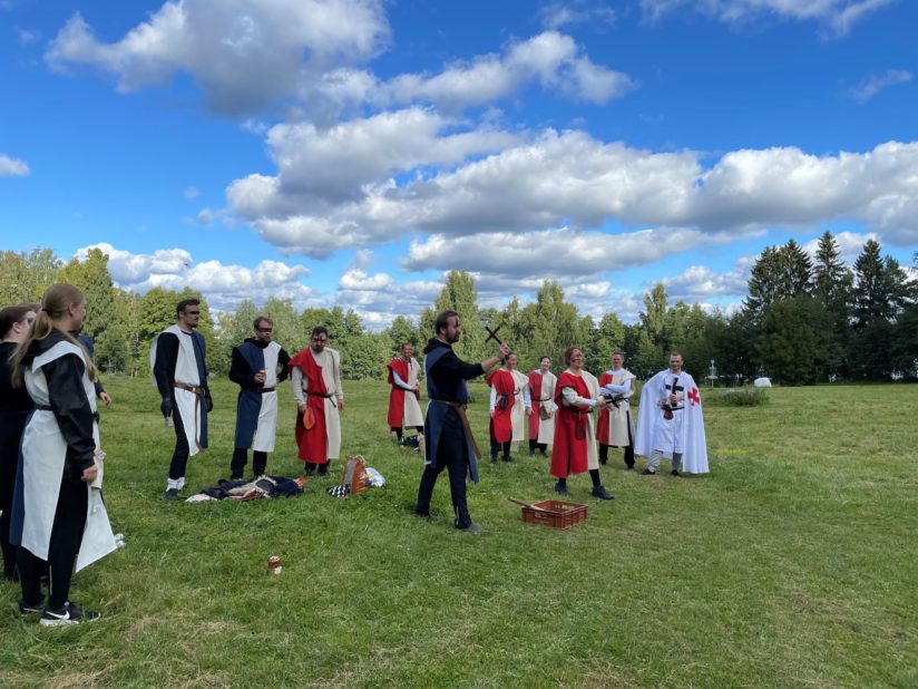 Kaveriporukka heittämässä heittoristejä nurmikentällä.