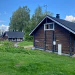 Puolukka mökki kesäisessä maisemassa, taustalla Lakka ja Varpu mökit sekä Iso-Roine.