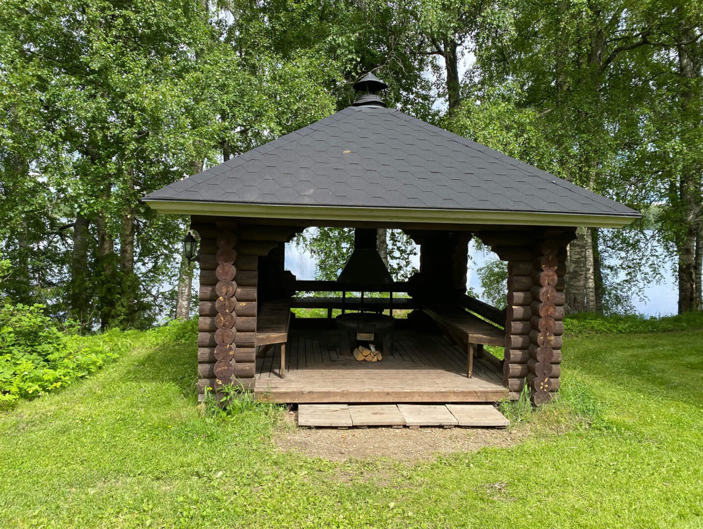 Pyöröhirsinen ruskea grillikatos nurmikolla Iso-Roine järven rannalla.